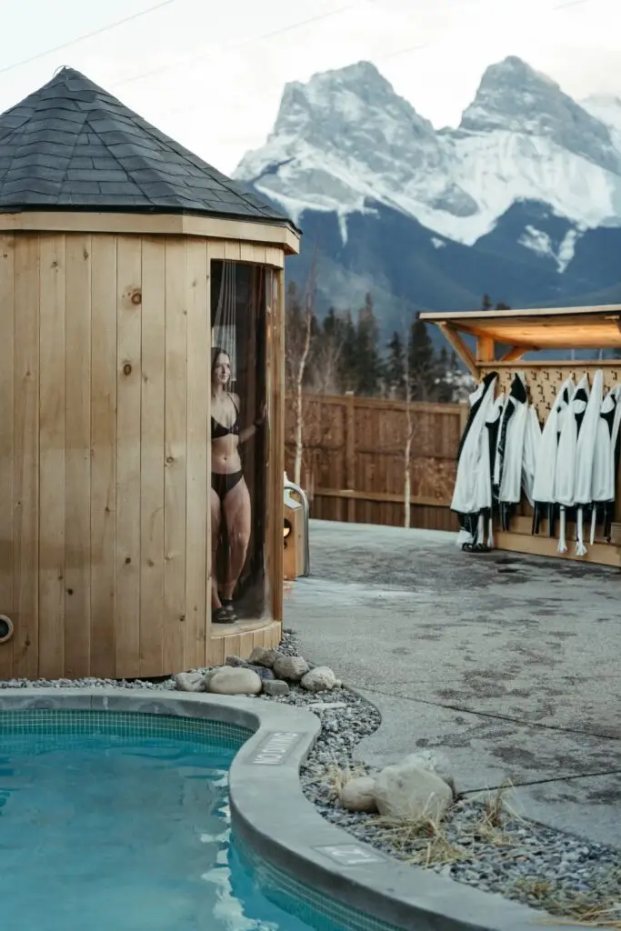 Woman in bikini in cedar barrel sauna by hot tub with mountains