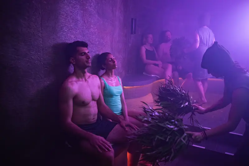 Couple relaxing in a steamy lodge with birch veniks