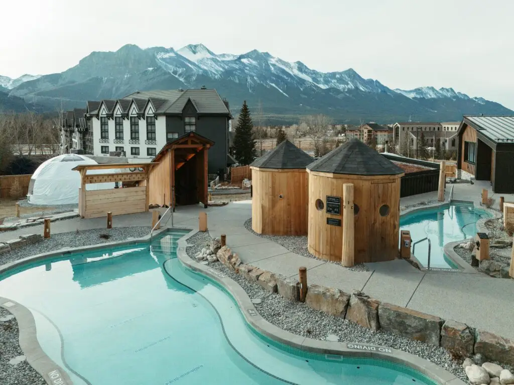 Outdoor spa pools with mountain views, featuring wooden saunas and a geodesic dome.