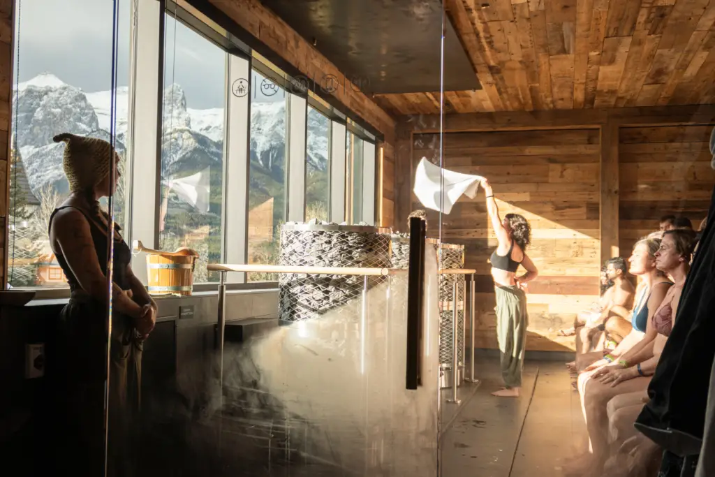 Nordic spa day Canmore: People relaxing in a steamy sauna with mountain views.