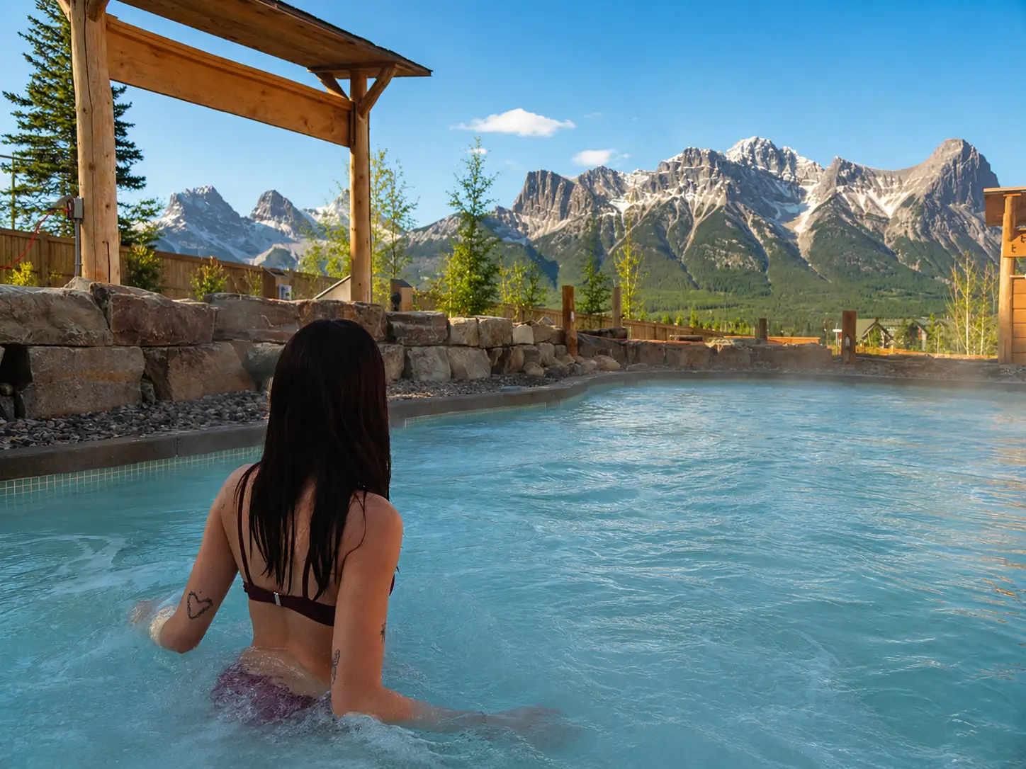 Woman in hot pool overlooking Canadian Rockies, Everwild vs Kananaskis Nordic Spa