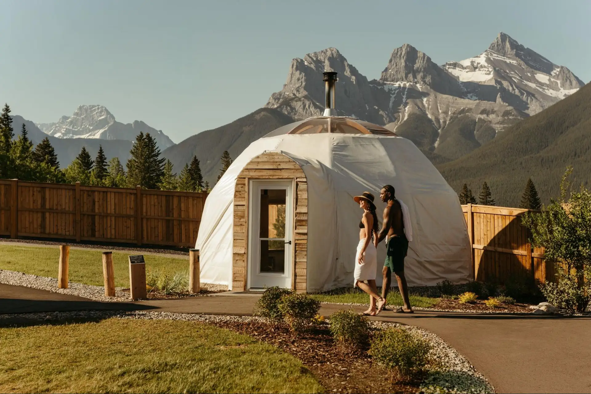 Couple walking towards Everwild Canmore spa dome with mountains