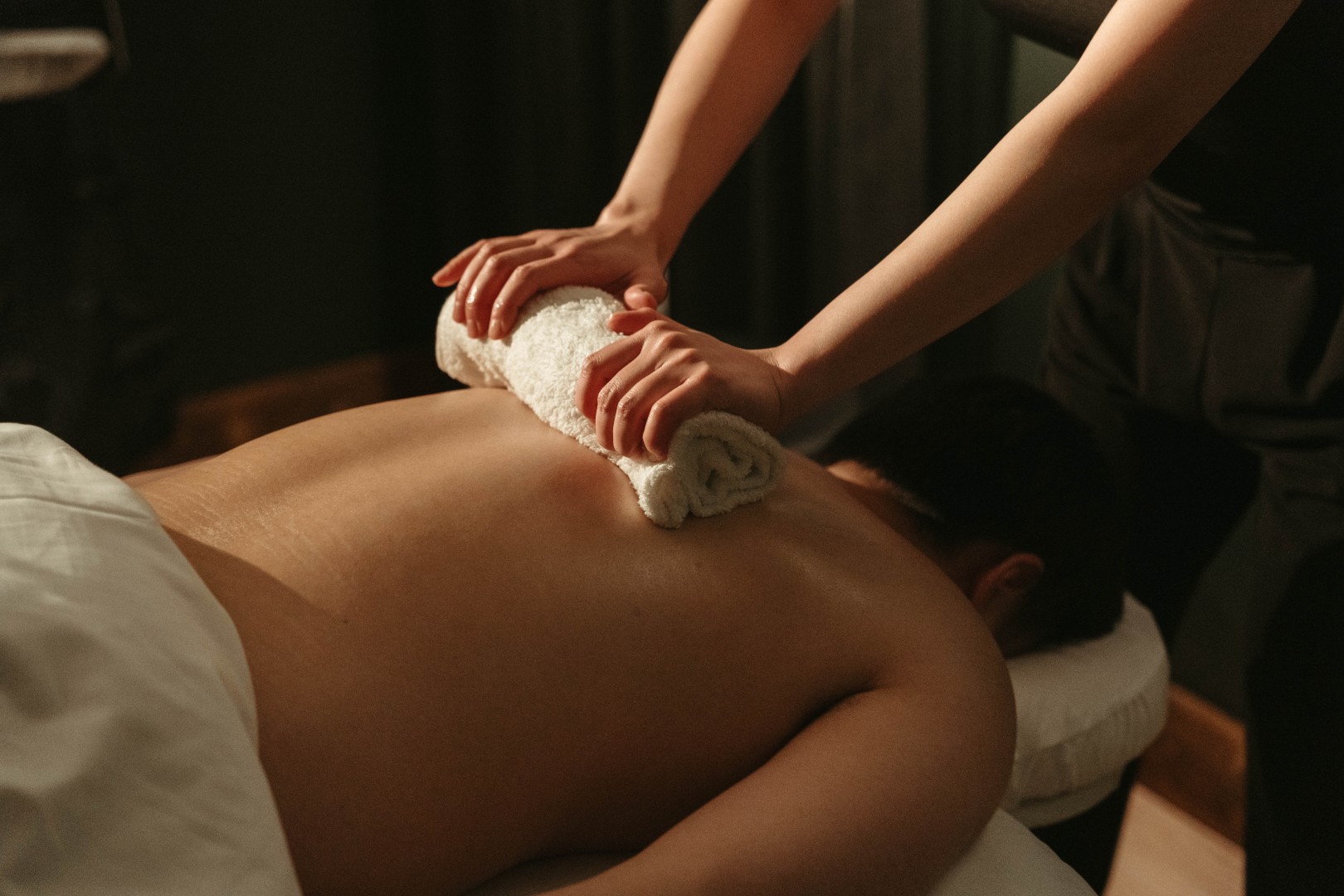 Hands giving a relaxing massage with a towel on a person's back, offering massage in Canmore.